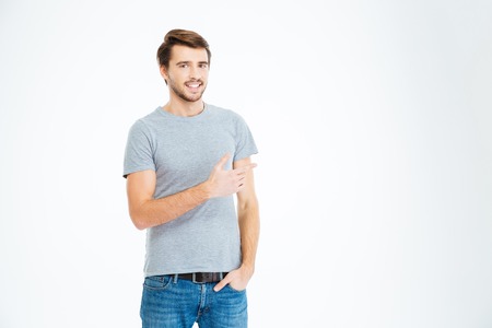 Happy casual man pointing finger away at copyspace isolated on a white backgroundの写真素材