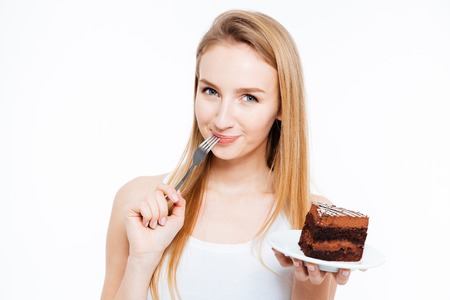 Attractive smiling young woman eating piece of chocolate cake over white backgroundの写真素材