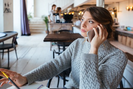 Young woman talking on the phone in cafeの写真素材