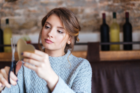 Beautiful woman cutting heart from paperの写真素材