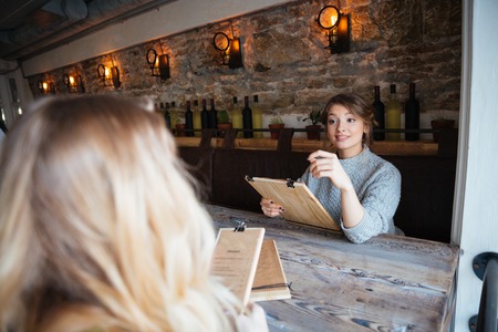 Smiling two women making order in restaurantの写真素材