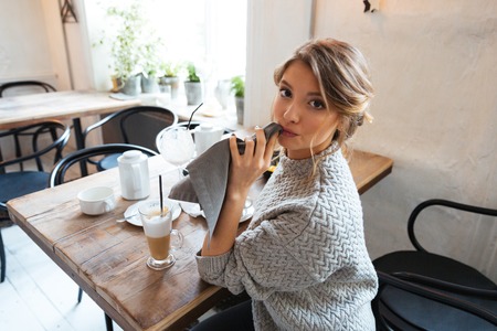 Woman wipes her lips with a napkin after eating in cafe and looking at cameraの写真素材