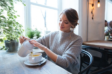 Happy woman drinking tea in cafeの写真素材