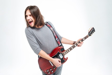 Crazy excited young man screaming and playing electric guitar over white backgroundの写真素材