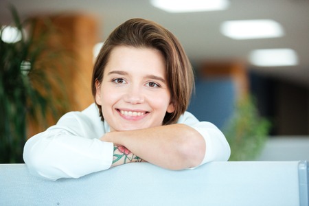 Closeup of attractive cheerful young woman smiling in officeの写真素材