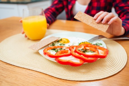 Closeup of plate with healthy breakfast with fresh fried eggs for young woman sitting on the kitchenの写真素材