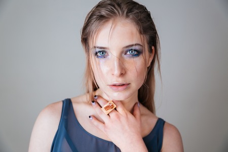 Beauty portrait of a lovely woman with blue eyes looking at camera over gray backgroundの写真素材