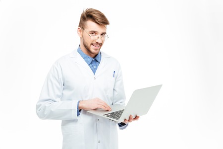 Happy male doctor using laptop computer isolated on a white background