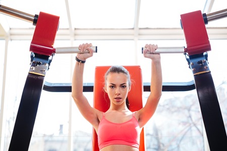Attractive focused young sportswoman doing exercises in gym