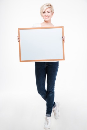 Full length portrait of a smiling woman holding blank board isolated on a white backgroundの写真素材
