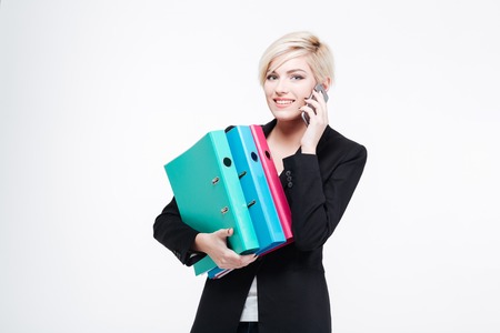 Happy businesswoman holding folders and talking on the phone isolated on a white backgroundの写真素材