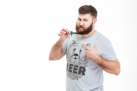 Brutal bearded man standing and showing small braid on his beard over white backgroundの写真素材
