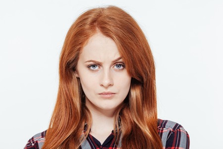 Serious redhead woman looking at camera isolated on a white background