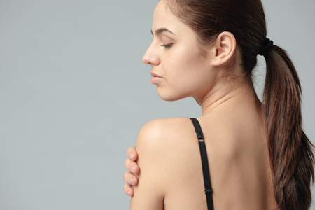 Sexy woman posing with naked shoulder over gray backgroundの写真素材