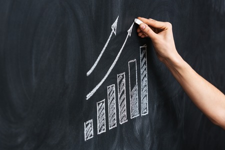 Closeup of hand drawing growth chart on blackboardの写真素材