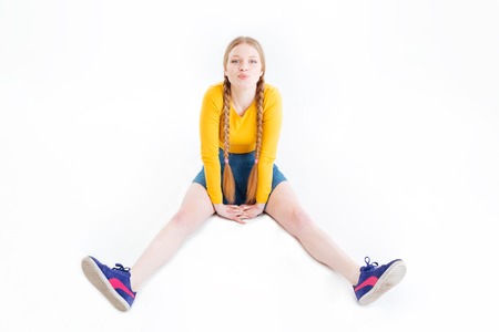 Funny female teenager sitting on the floor isolated on a white backgroundの写真素材