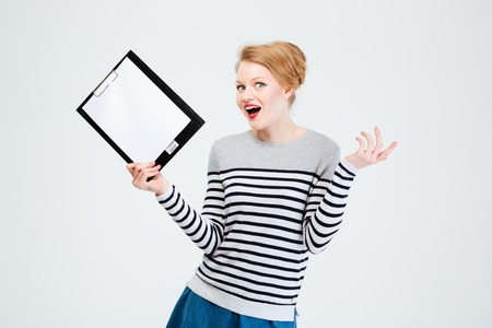 Amazed young woman holding clipboard isolated on a white backgroundの写真素材