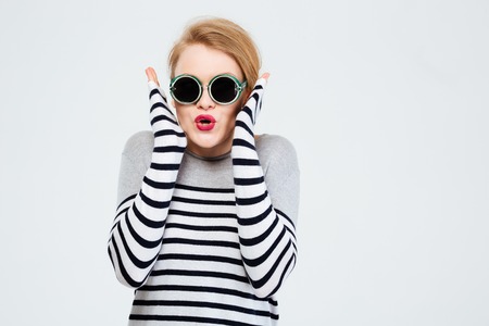 Amazed woman in sunglasses standing isolated on a white backgroundの写真素材