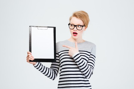Amazed young woman showing blank clipboard isolated on a white backgroundの写真素材