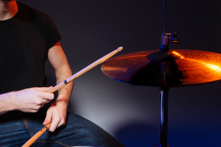 Closeup of hands of drummer with sticks playing drums over dark backgroundの写真素材