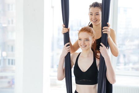 Smiling cute redhead young woman doing antigravity yoga in studioの写真素材
