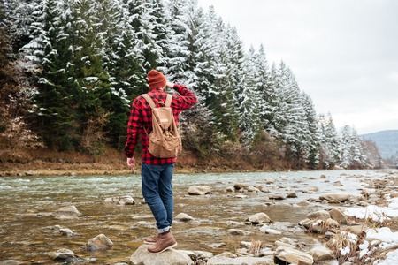 Man standing on the stone in river and looking away with forest on backgroundの写真素材