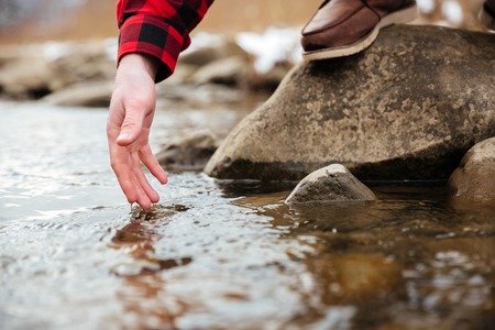 Closeup portrait of a male hand testing water in riverの写真素材