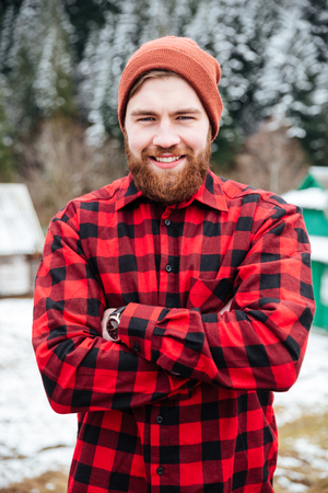Cheerful attractive bearded man standing with hands folded in winter villageの写真素材