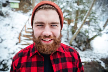 Cheerful bearded young man in checkered shirt in winter forestの写真素材