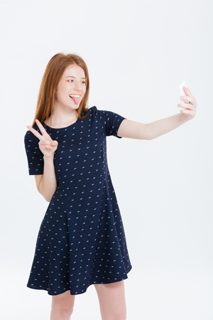 Funny woman making selfie photo on smartphone isolated on a white backgroundの写真素材
