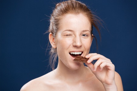 Woman eating chocolate over blue backgorund