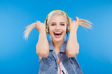 Cheerful female teenager holding her ponytails over blue backgroundの写真素材