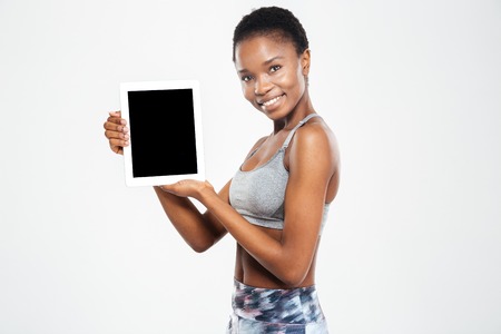 Happy afro american woman showing blank tablet computer screen isolated on a white backgroundの写真素材