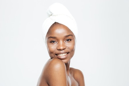 Happy afro american woman with towel on head looking at camera isolated on a white backgroundの写真素材