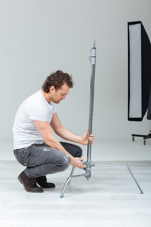 Male photographer preparing lighting equipment in studioの写真素材