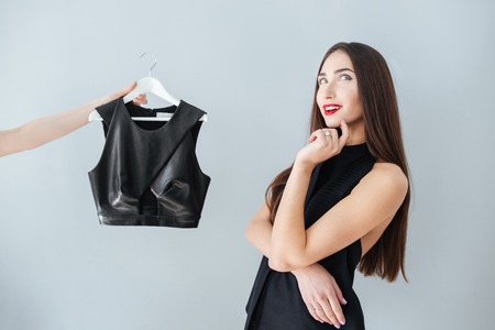 Happy woman thinking about buying clothes in store