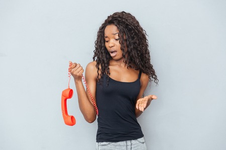 Sad woman holding retro phone tube over gray backgroundの写真素材
