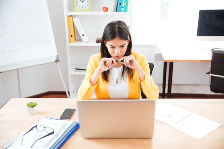 Businesswoman sitting at the table with laptop computer in officeの写真素材