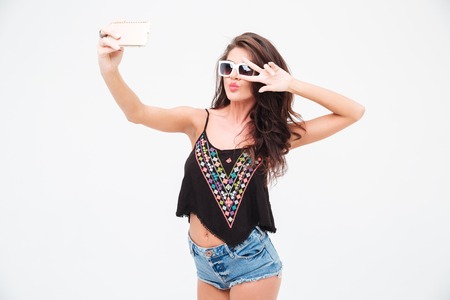 Stylish woman making selfie photo on smartphone isolated on a white backgroundの写真素材