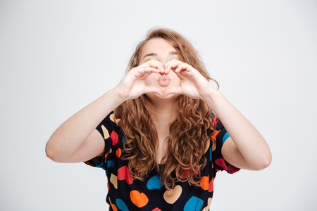 Woman showing heart gesture with fingers isolated on a white backgroundの写真素材
