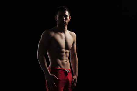 Silhouette of a muscular man standing over dark backgroundの写真素材