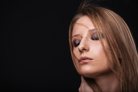 Beauty portrait of a woman with fresh skin and closed eyes over black backgroundの写真素材