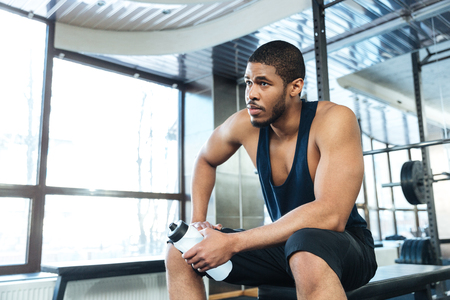 Afro american fitness man resting on the bench in the gymの写真素材