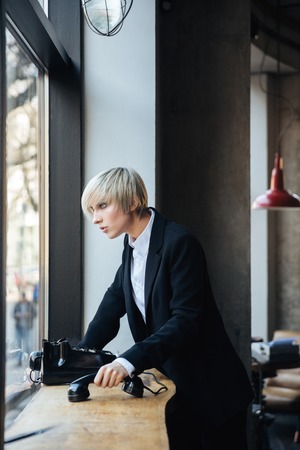 Serious pretty girl looking at the window and holding in cafe