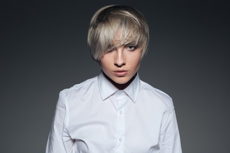 Portrait of a stylish woman looking at camera over gray backgroundの写真素材