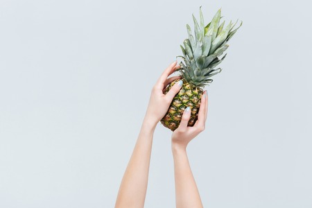 Closeup portrait of female hands holding ananas isolated on a white backgroundの写真素材