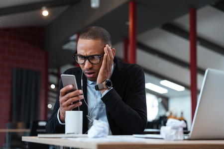 Surprised businessman looking at the smartphone and wears earphonesの写真素材