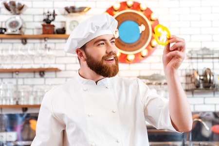 Smiling attractive cook cheif holding slice of yellow bell pepper  on the kitchenの写真素材