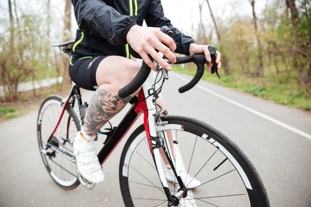 Closeup of tattoed young woman riding bike in park