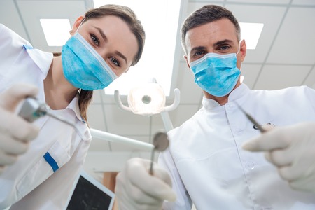 Two dentists making treatment to a patient in clinicの写真素材